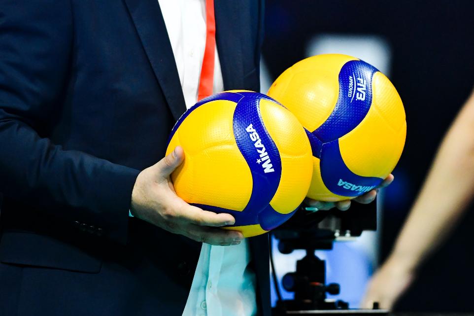 Une personne tenant deux ballons de volley